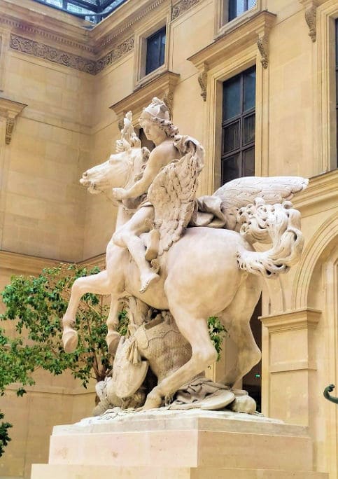 Valkoinen marmorisveistos, jossa siivekäs Pegasus ja ratsastava hahmo museon sisäpihalla.