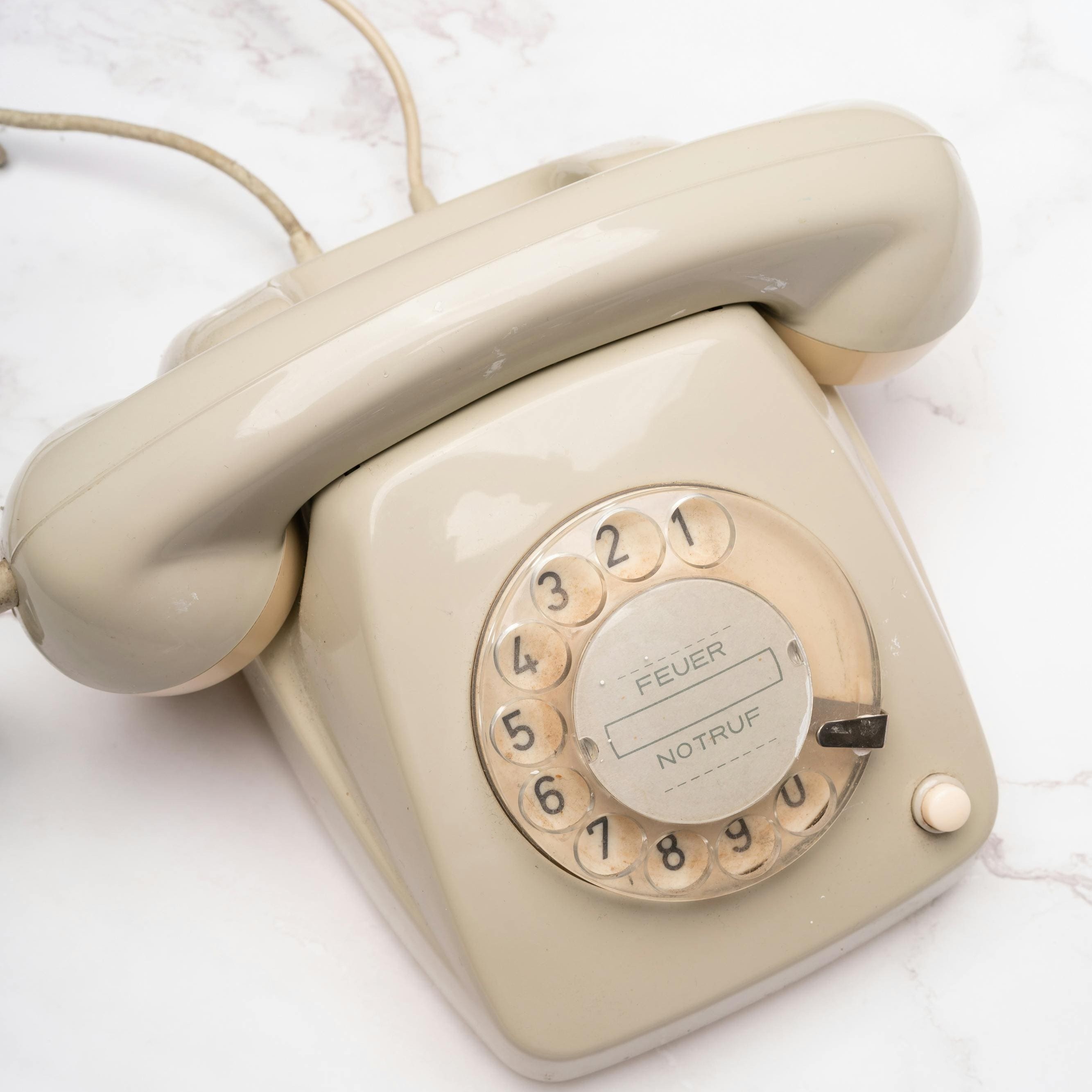 Beige pyöreä valintapuhelin, jossa saksankieliset hätäpuhelinnumerot 'FEUER' ja 'NOTRUF'.
